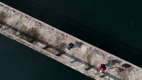 A-aerial-view-looking-done-at-people-walking-along-a-jetty-out-at-sea