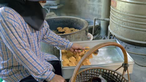 Bakery-worker-taking-out-Khanom-Farang-Kudeejeen-cupcakes-from-hot-oven