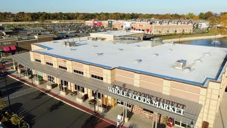 Shopper-enters-Whole-Foods-Market-grocery-store,-unique-shadow-cast-by-sign,-aerial-drone-view