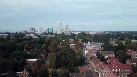 Aerial-Push-Old-Salem-in-Foreground-with-Winston-Salem-NC-Skyline-in-Background