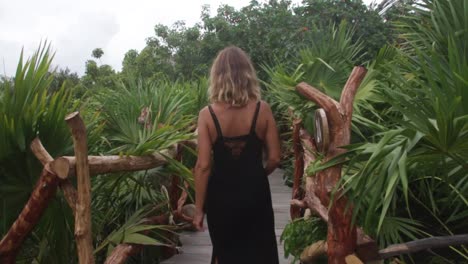 blonde-woman-walks-on-a-wood-bridge-in-the-jungle
