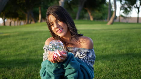 A-cute-young-hispanic-woman-smiling-happily-in-a-park-with-a-magic-crystal-ball