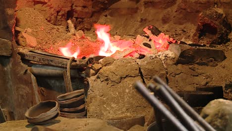 blacksmith-working-on-bowls-with-tongs-in-front-of-an-ancient-traditional-fire-oven