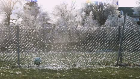 SLOW-MOTION:-A-soccer-ball-slams-into-an-icy-fence-which-explodes-the-shattered-ice-into-the-air