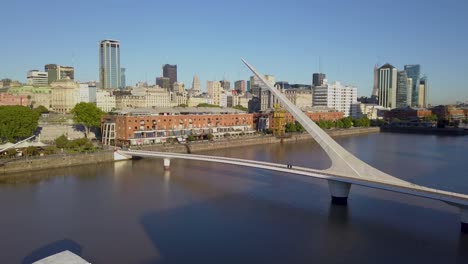 Cinematic-Aerial-Shot-Rising-Over-Puente-De-La-Mujer,-Revealing-Downtown-Buenos-Aires