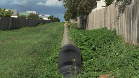 TILT-UP-Of-Large-Water-Pipeline-Down-A-Grassy-Avenue-In-A-Suburb