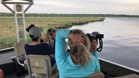 Photo-Safari-guests-photograph-birds-along-the-Chobe-River,-Africa