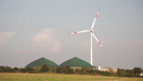 Wide-shot-of-spinning-windmill-with-bio-gas-facility