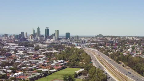 Aerial,-freeway-leading-to-high-rise-buildings-in-distance,-pedestal-up,-Perth,-Australia