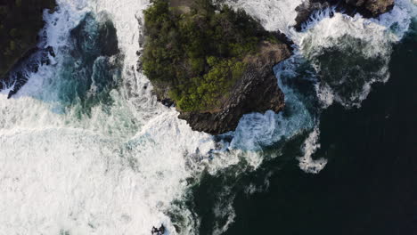 Scenic-aerial-view-of-big-waves-crash-against-small-islands-near-coast