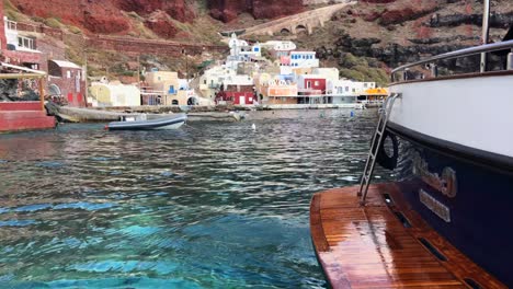 Yacht-docked-in-turquoise-water-at-port-of-Santorini-in-Greece-with-harbor-view