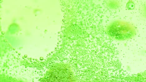 macro-shot-of-many-small-green-bubbles-sparkling-in-water-and-a-big-bubble-falling-to-ground-out-of-focus-with-a-bright-background