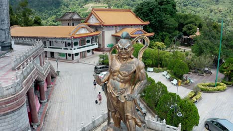 Guardian-warrior-statue-at-Kek-Lok-Si-Buddhist-Temple-in-the-suburb-of-Air-Itam,-Aerial-orbit-reveal-drone-shot