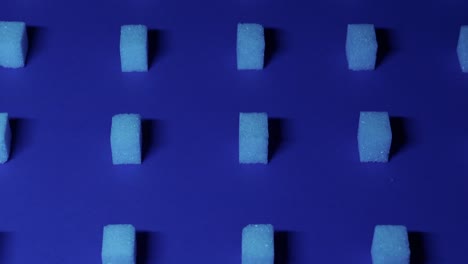 4k-Langsame-Neigungsansicht-Eines-Einzigartigen-Kubischen-Hintergrunds-Mit-Weißen-Zuckerwürfeln,-Die-In-Reihen-Auf-Einem-Dunkelblauen-Hintergrund-Angeordnet-Sind,-3D-Effekt
