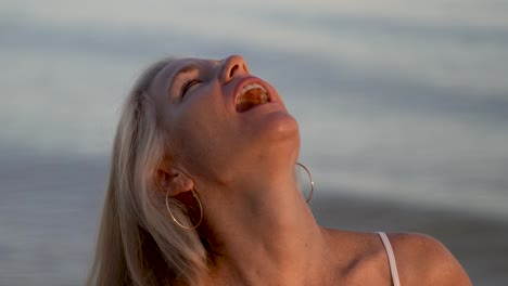 Portrait-of-beautiful-mature-blonde-woman-on-the-beach-at-sunset-flirting-with-the-camera