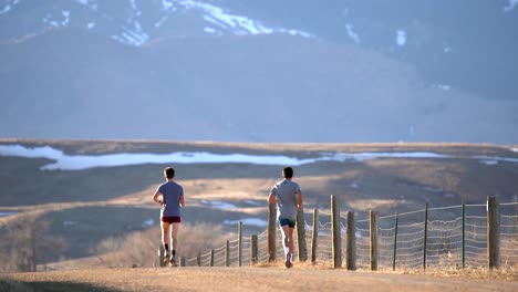 Two-men-running-on-a-dirt-road-in-countryside