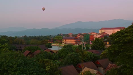 Hot-air-balloon-flying-over-Laos-mountain-countryside-at-sunset,-aerial-view