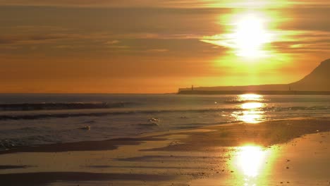 Golden-coastal-sunrise-over-sandy-beach,-spain