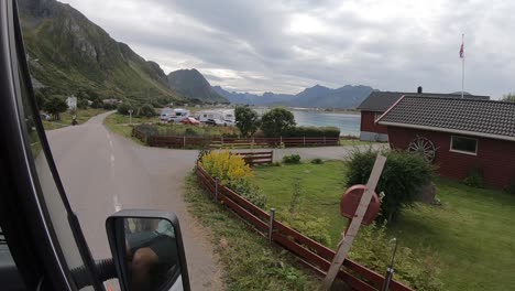 Wide-shot-from-the-window-of-a-campervan-driving-through-the-fjords-of-Lofoten,-Norway-coming-into-Ramberg-and-Rambergstranda-with-houses-next-to-the-ocean