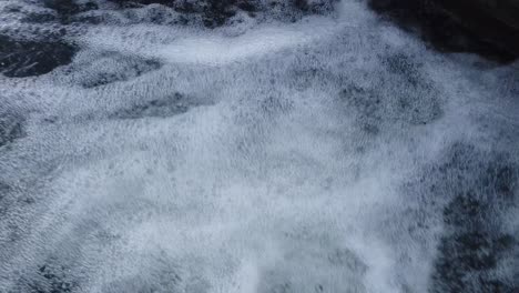 Water-stream-in-a-mini-waterfall-with-bubbles-on-a-cold-winter