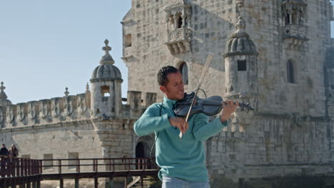 Smiling-Street-Violinist-Playing-Music-at-La-Torre-De-Belem-in-Lisbon,-Portugal