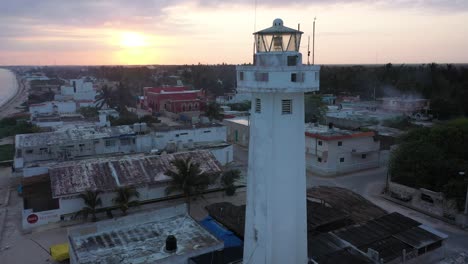 Aerial-trucking-shot-to-the-right-at-sunrise-with-closeup-of-lighthouse-in-Telchac-Puerto-in-Yucatan,-Mexico