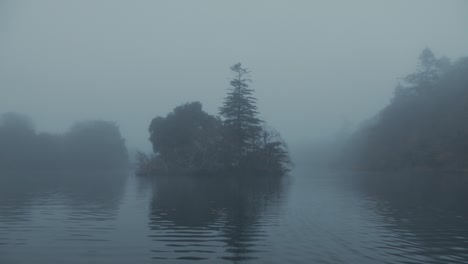 Atmospheric-tracking-towards-tree-covered-island-surrounded-with-fog