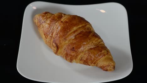 Sabroso-Desayuno-De-Croissant-De-Mantequilla-Francesa-En-Plato-Blanco-Sobre-Mesa-Negra,-Primer-Plano