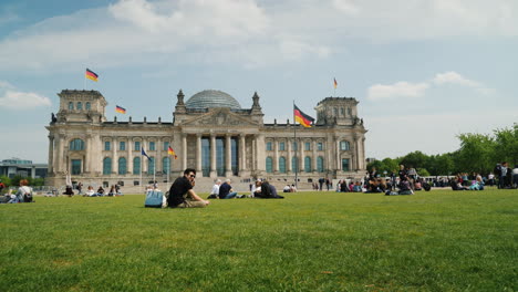 Tourists-And-Locals-Rest-On-A-Green-Lawn-Near-The-Bundestag-Berlin