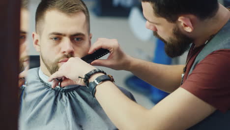 Barber-Cuts-And-Shapes-Client's-Beard-In-Barbershop