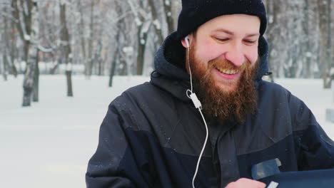 Smiling-Man-Uses-Smartphone-In-Winter-Park