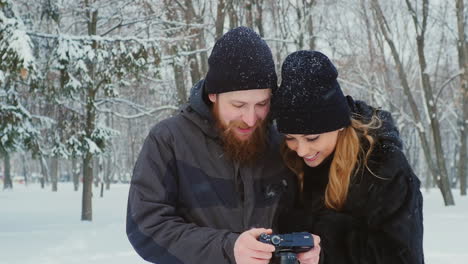 Young-Couple-Viewing-Photos-On-Camera-In-Winter