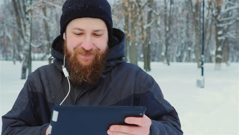 Smiling-Man-Uses-Tablet-In-Winter-Park-01