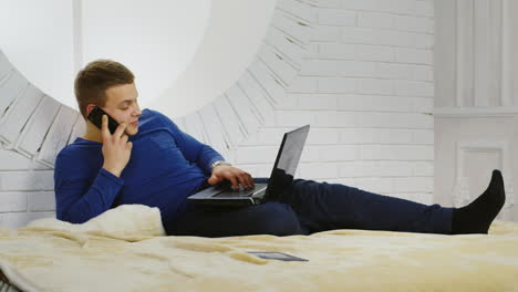Young-Man-Casually-Using-a-Phone-and-Laptop