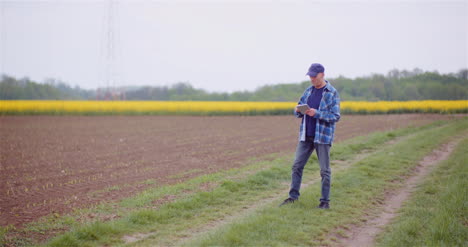 Agricultor-Agrícola-Examinando-Cultivos-Y-Campo-Agricultor-Adulto-Usando-Tableta-Digital
