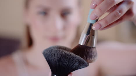 Young-Woman-Using-Brush-And-Powder-While-Doing-Make-Up-