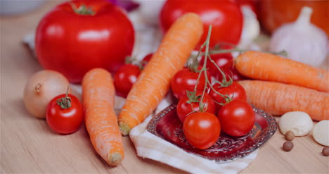Nahaufnahme-Von-Verschiedenen-Gemüsesorten-Auf-Dem-Tisch,-Die-Frische-Kirschtomaten-Rotieren,-Karotten,-Rote-Zwiebeln-Und-Knoblauch-3