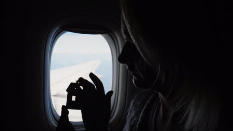 Woman-Holds-House-Figurine-by-Airplane-Window