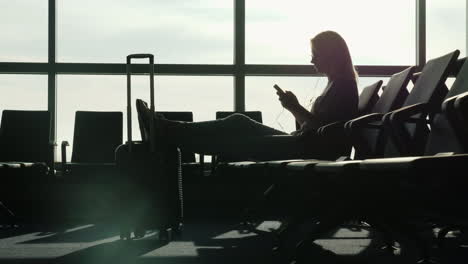 Woman-In-Airport-Uses-A-Smartphone