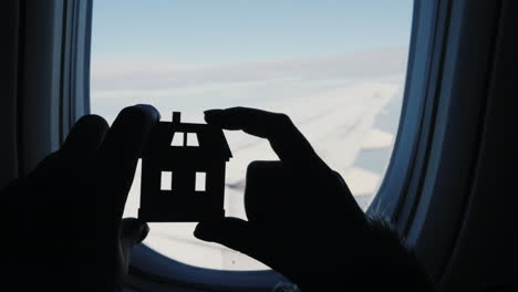 Hands-Holding-House-Silhouette-by-Plane-Wing