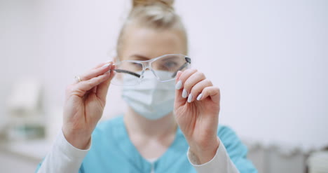 Female-Doctor-Wearing-Protective-Mask-On-Face-And-Cleaning-Glasses-Doctor-At-Healtcare-Clinic