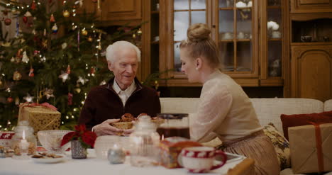Young-Woman-Giving-Christmas-Present-To-Grandfather-At-Home