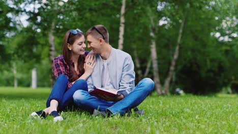 Young-Man-And-A-Woman-Reading-A-Book-In-The-Park-They-Sit-On-A-Green-Lawn-Hd-Video