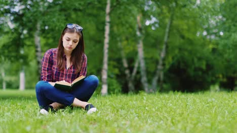 Attractive-Female-Student-Reading-A-Book-In-The-Park-Sitting-On-The-Lawn-Hd-Video