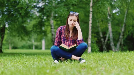 Attractive-Female-Student-Reading-A-Book-In-The-Park-Sitting-On-The-Lawn-Hd-Video