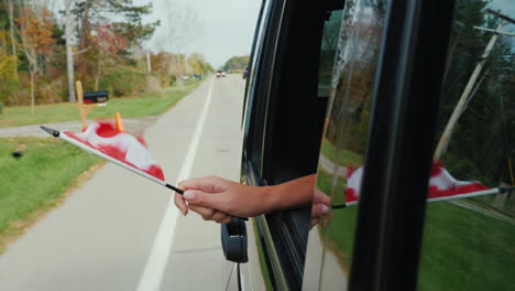 Hand-Holds-Canadian-Flag-Out-of-Car-Window