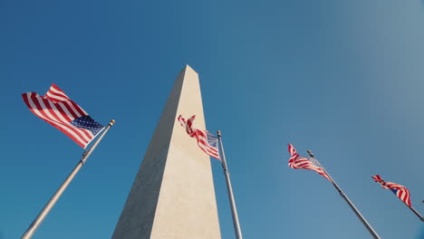Washington-Monument-In-Dc-Usa-American-Flags-Flap-Below-Low-Angle-Shot