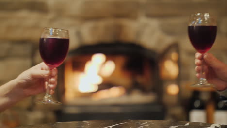 Clinking-Wine-Glasses-by-Burning-Fireplace