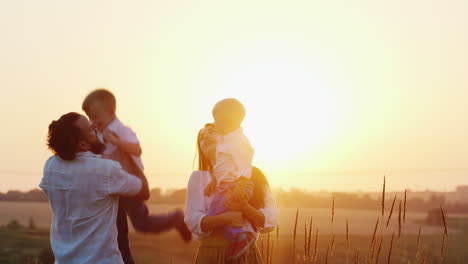 Young-Family-With-Two-Niños-Playing-On-Nature-On-The-Sunset