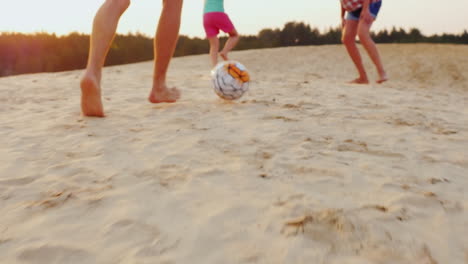 Family-Playing-Football-In-The-Frame-Of-The-Man-Legs-Hit-The-Ball-The-Ball-On-The-Sand
